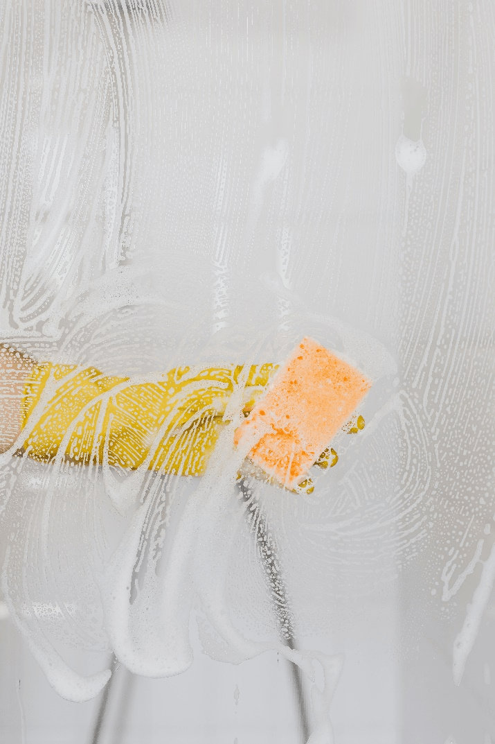 a person using a glove to clean glass doors in a bathroom